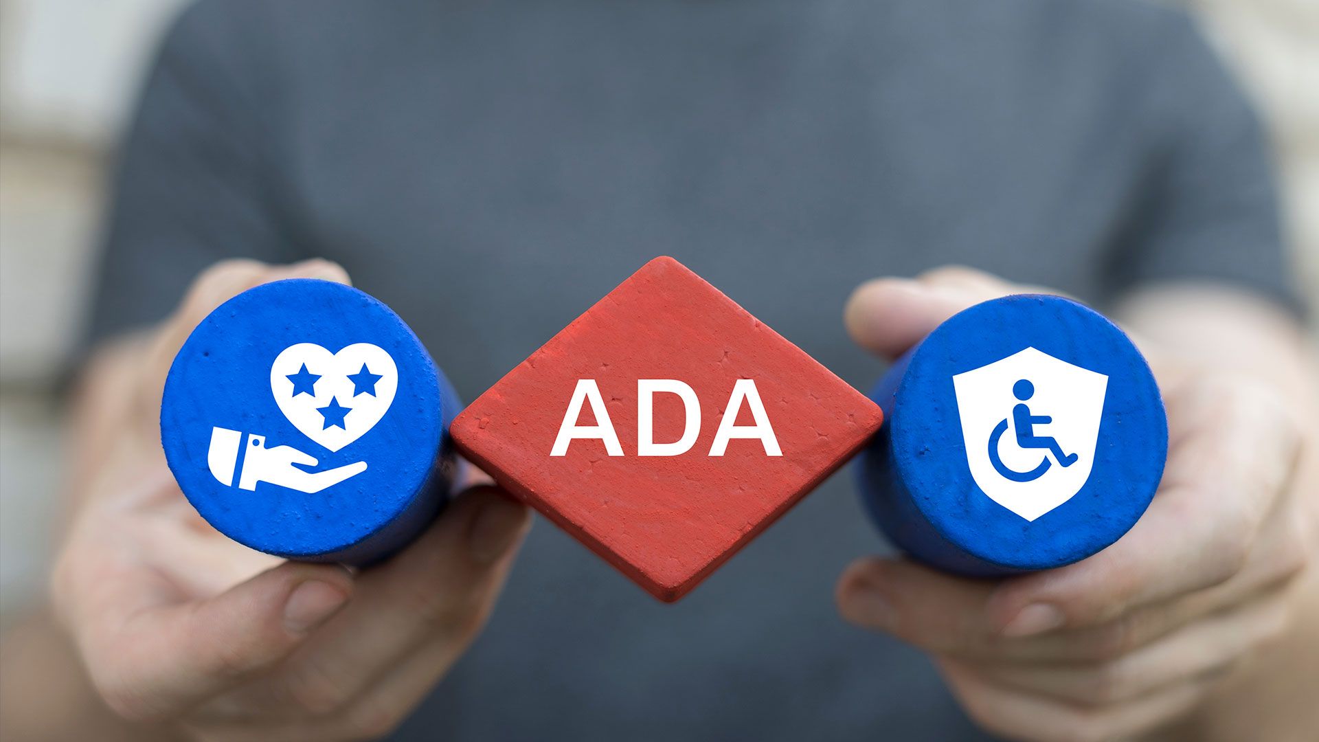 Hands holding wooden blocks labeled 'ADA' with accessibility symbols.