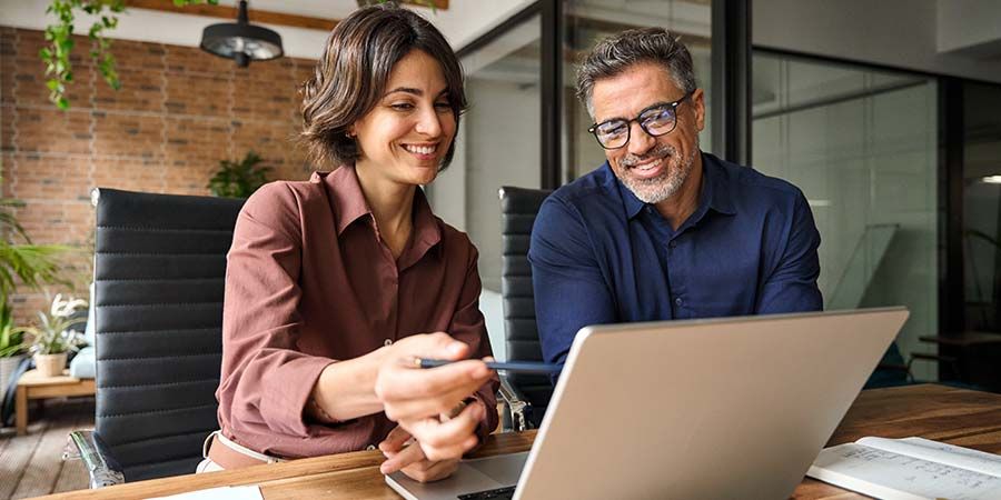 Two professionals collaborating while looking at a laptop.