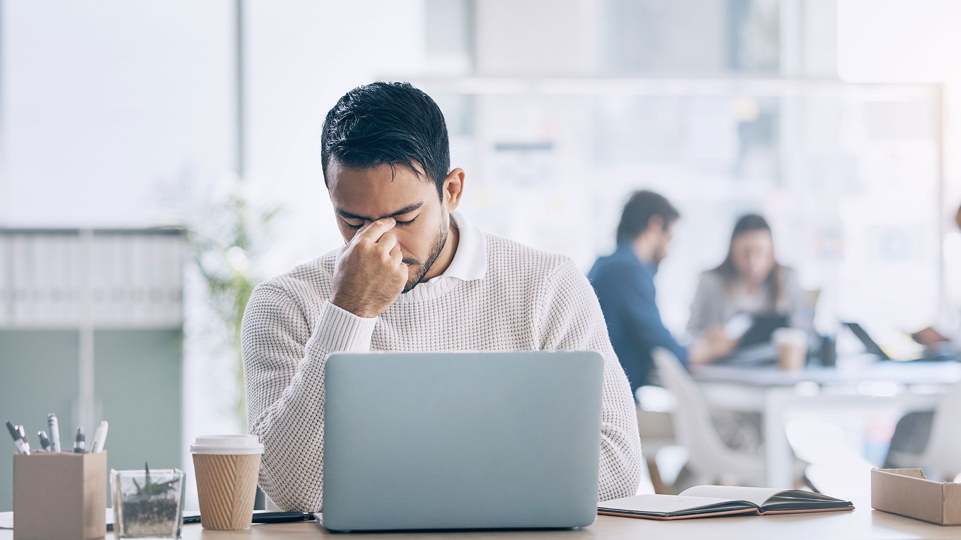 A frustrated professional at a desk with a laptop.