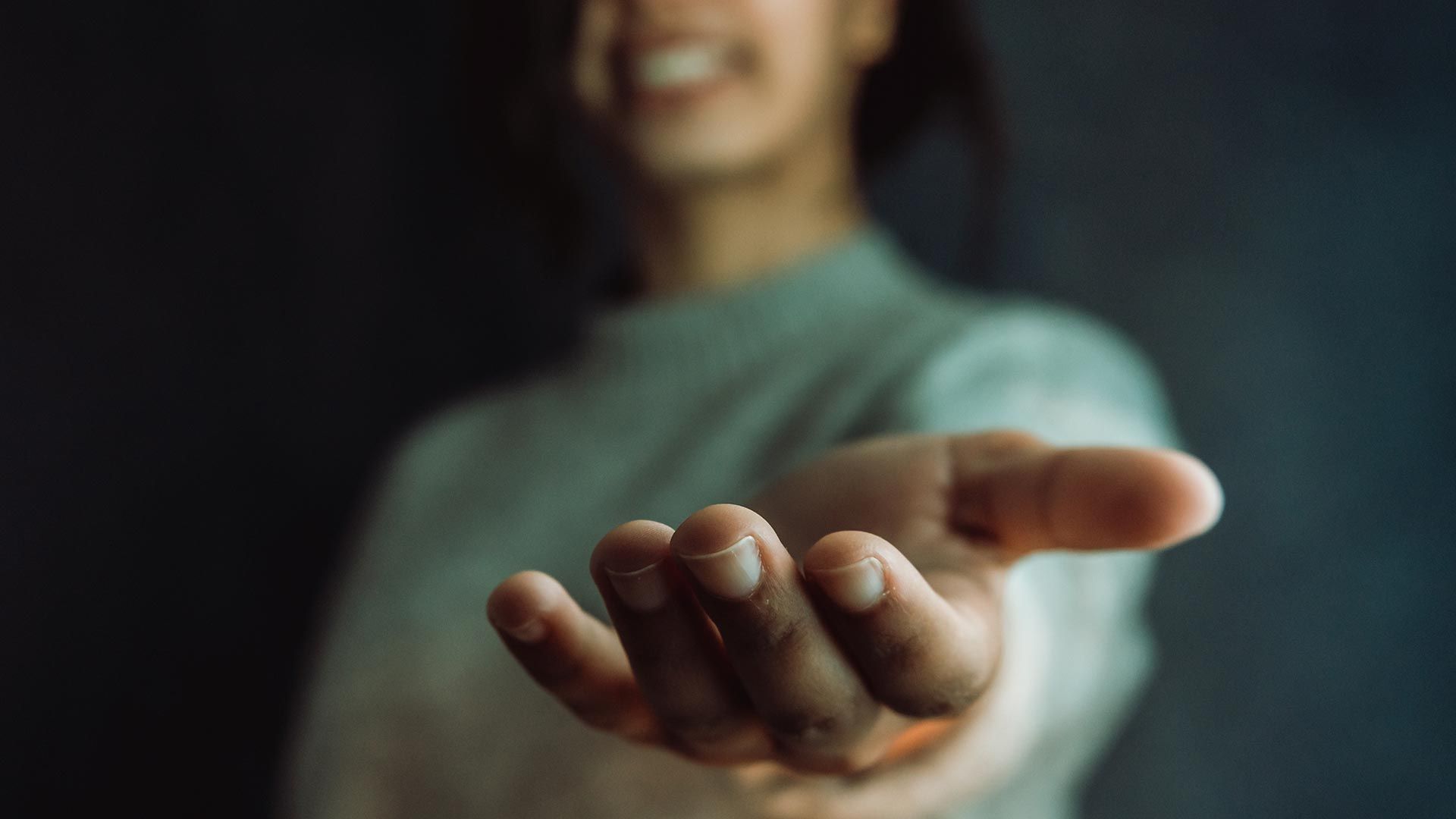 A person reaching forward with an outstretched hand.