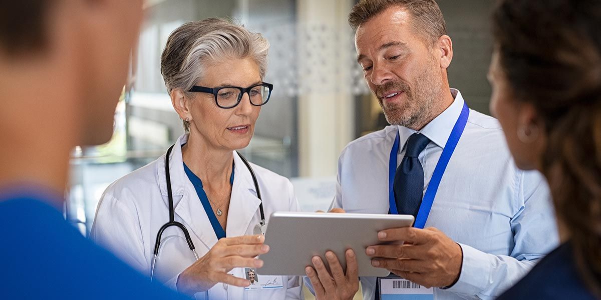 Doctors discussing information on a tablet in a medical setting.