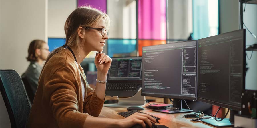 A software developer analyzing code on dual monitors.