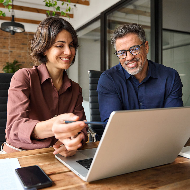 Two colleagues collaborating on a project using a laptop.